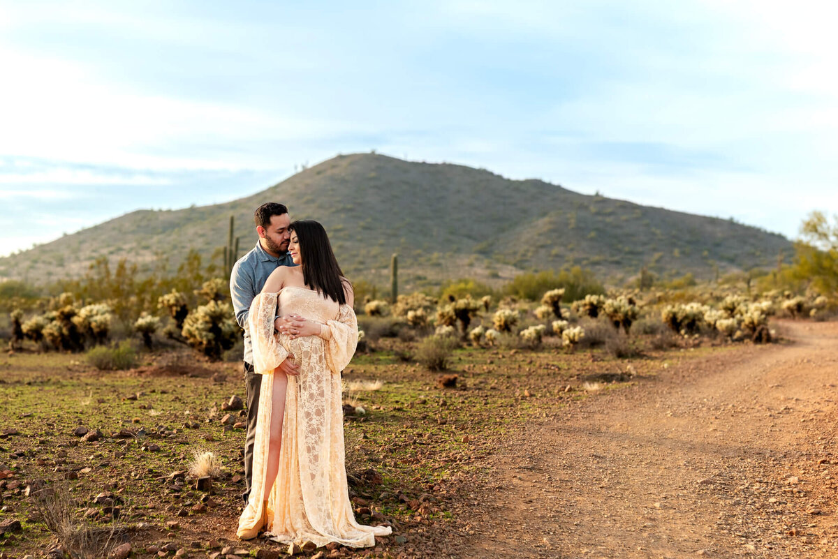 parents-to-be sharing a sweet moment cheek to cheek while cradling baby bump. Captured by Cactus & Pine Photography