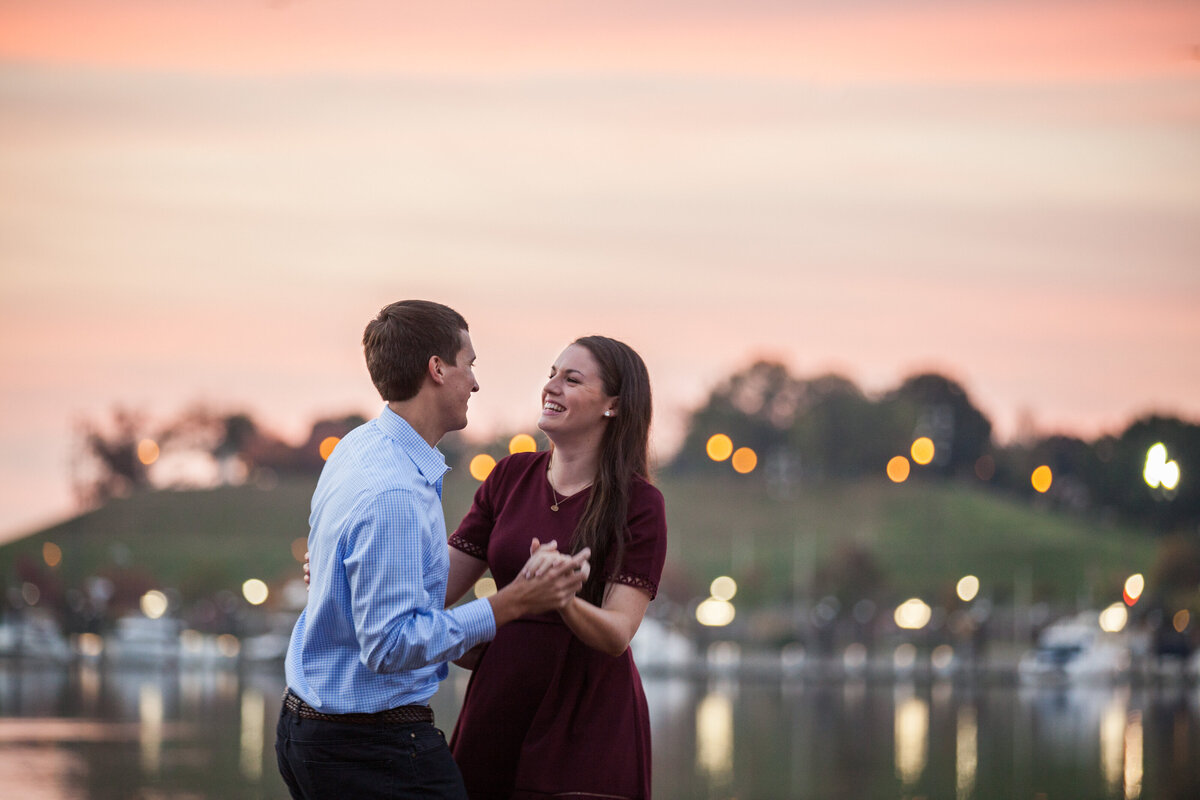 A couple holds hands with each other, dancing, under a sunset.