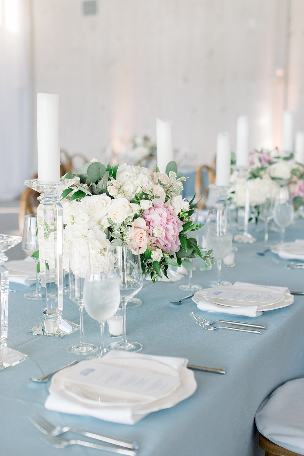 Details of a wedding reception table set up with blue linen and white and pink florals