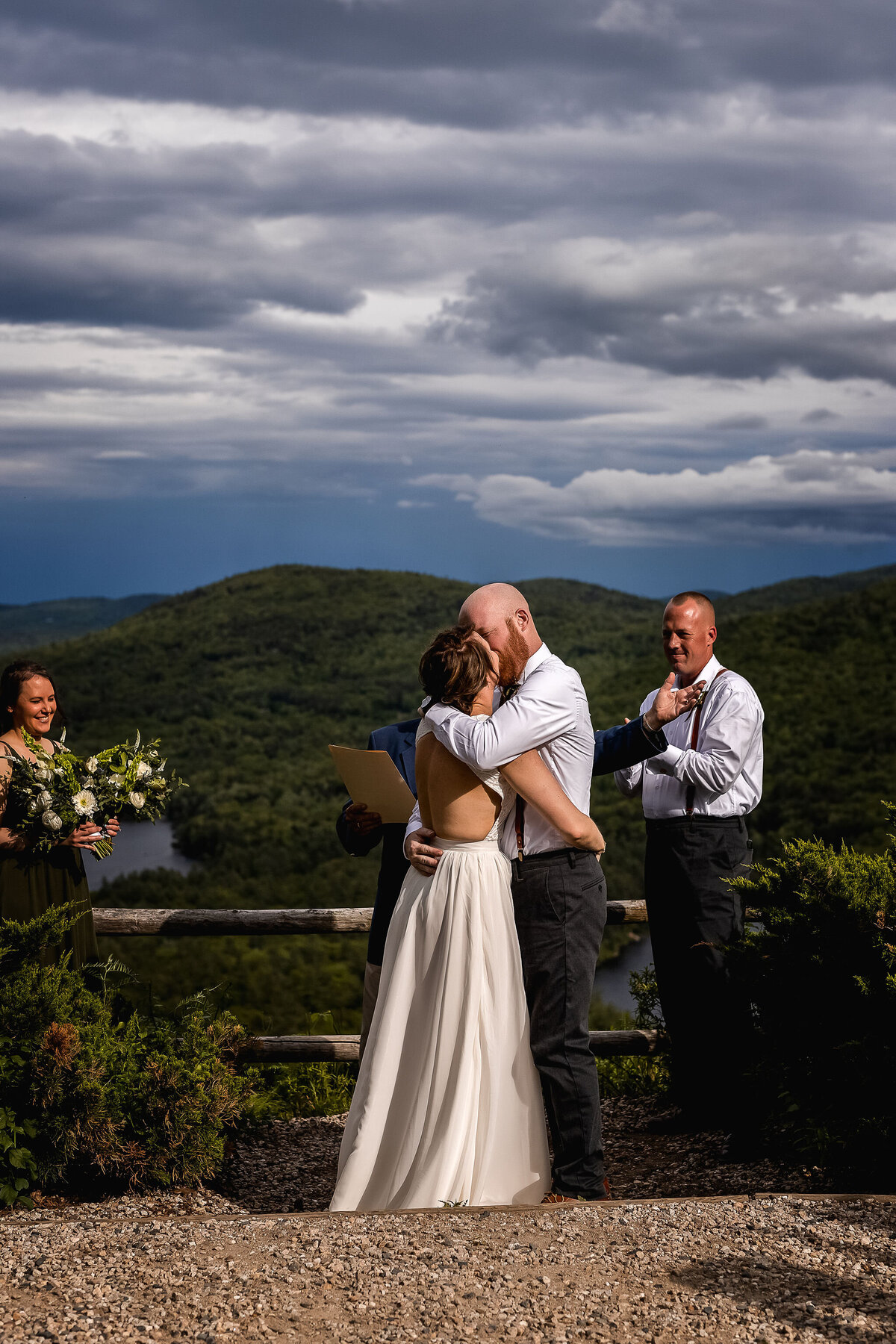 Bride and grooms first kiss with mountain views at spring wedding in Tamworth NH by Lisa  Smith Photography