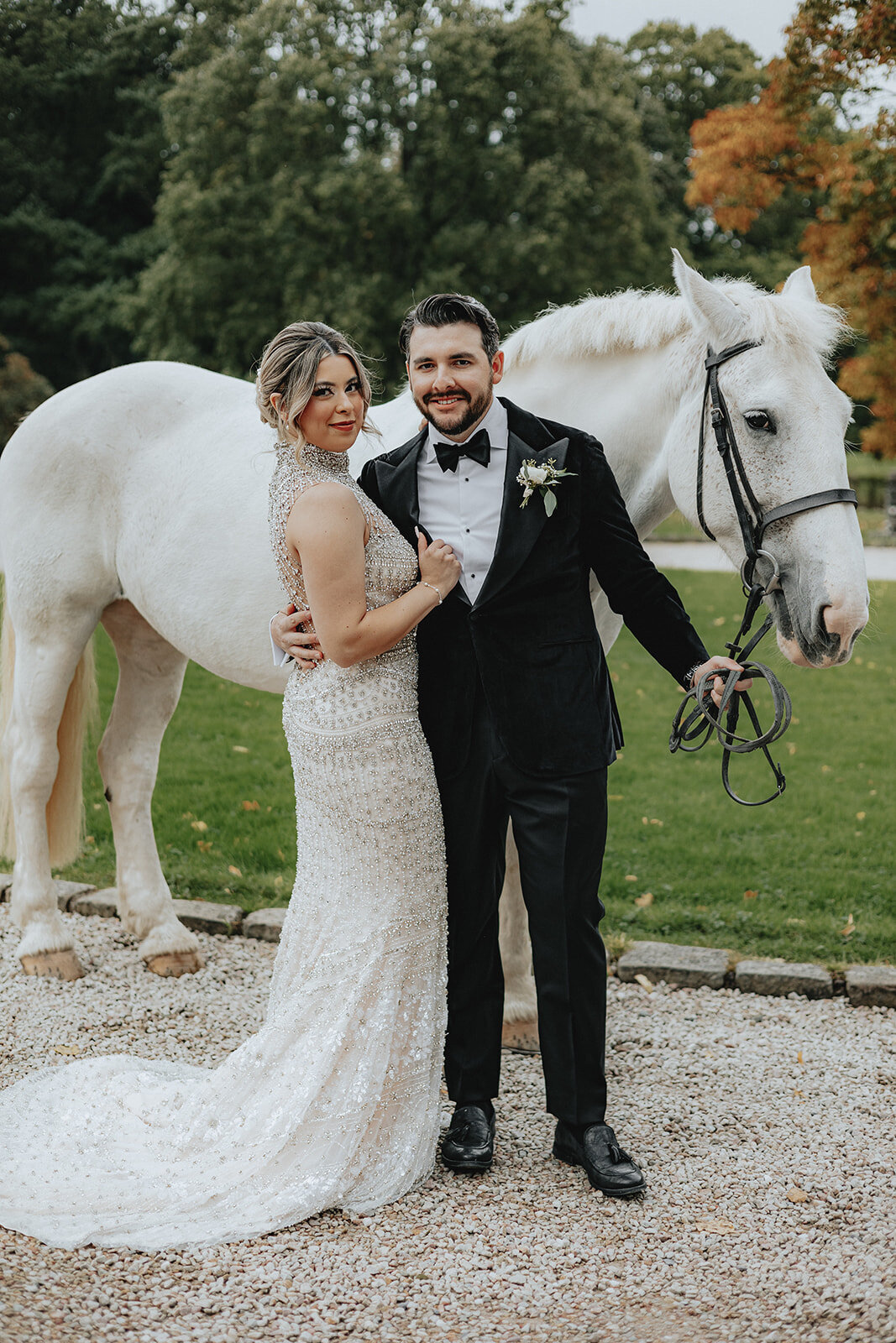 Bride and groom posing in front of white horse