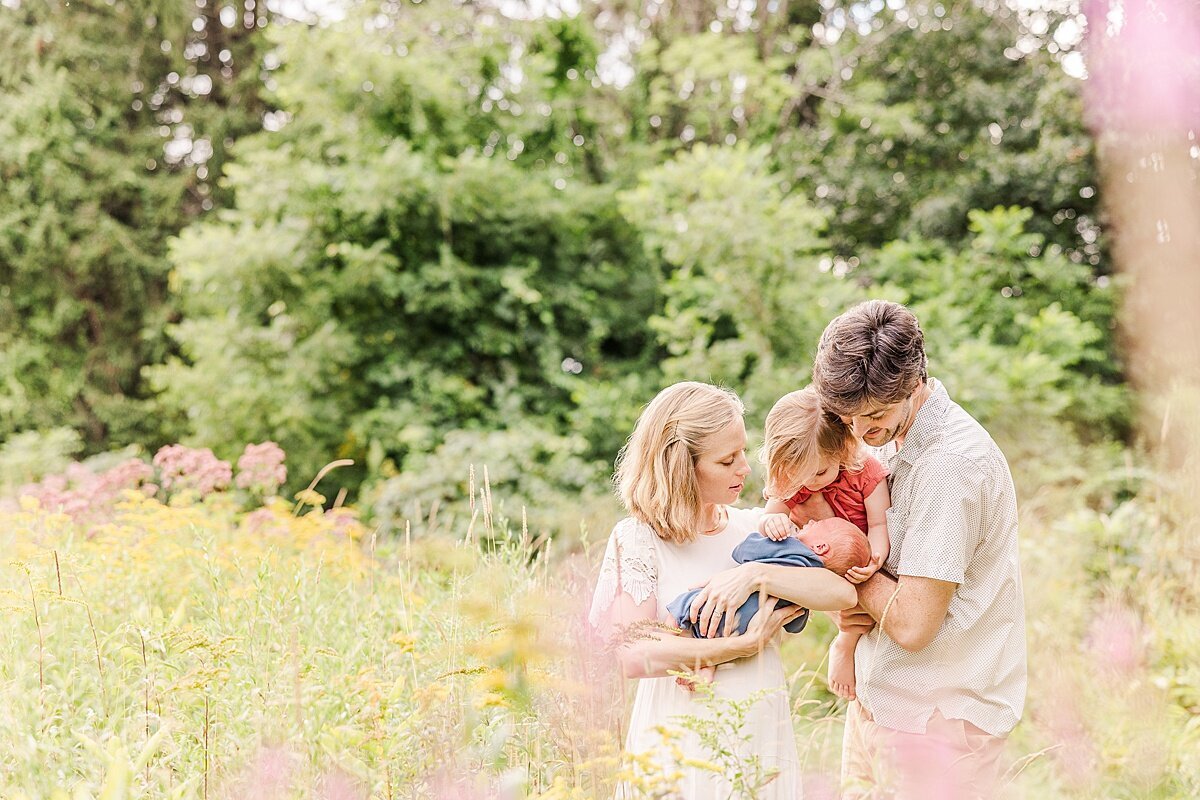 family snuggles in field during outdoor newborn photo session with Sara Sniderman Photography at Heard Farm in Wayland Massachusetts
