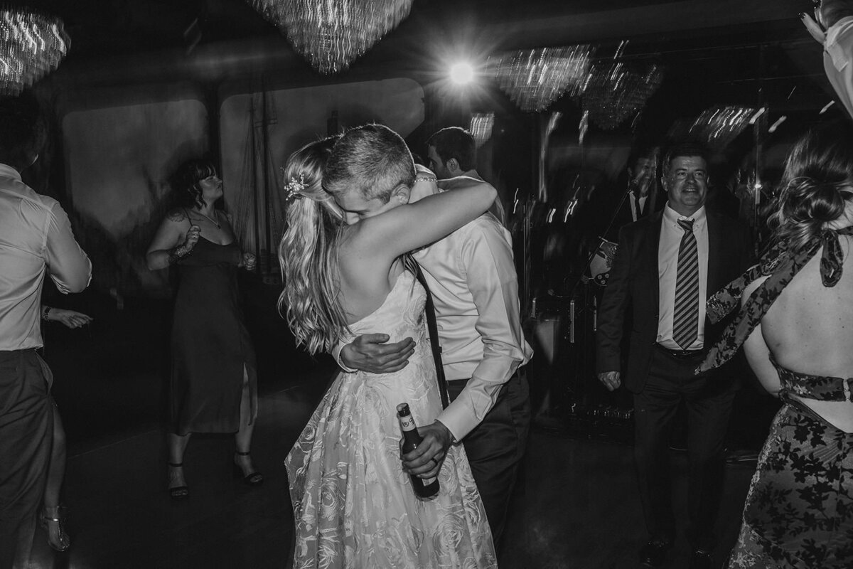 A newlywed couple hugging and dancing at their reception 
