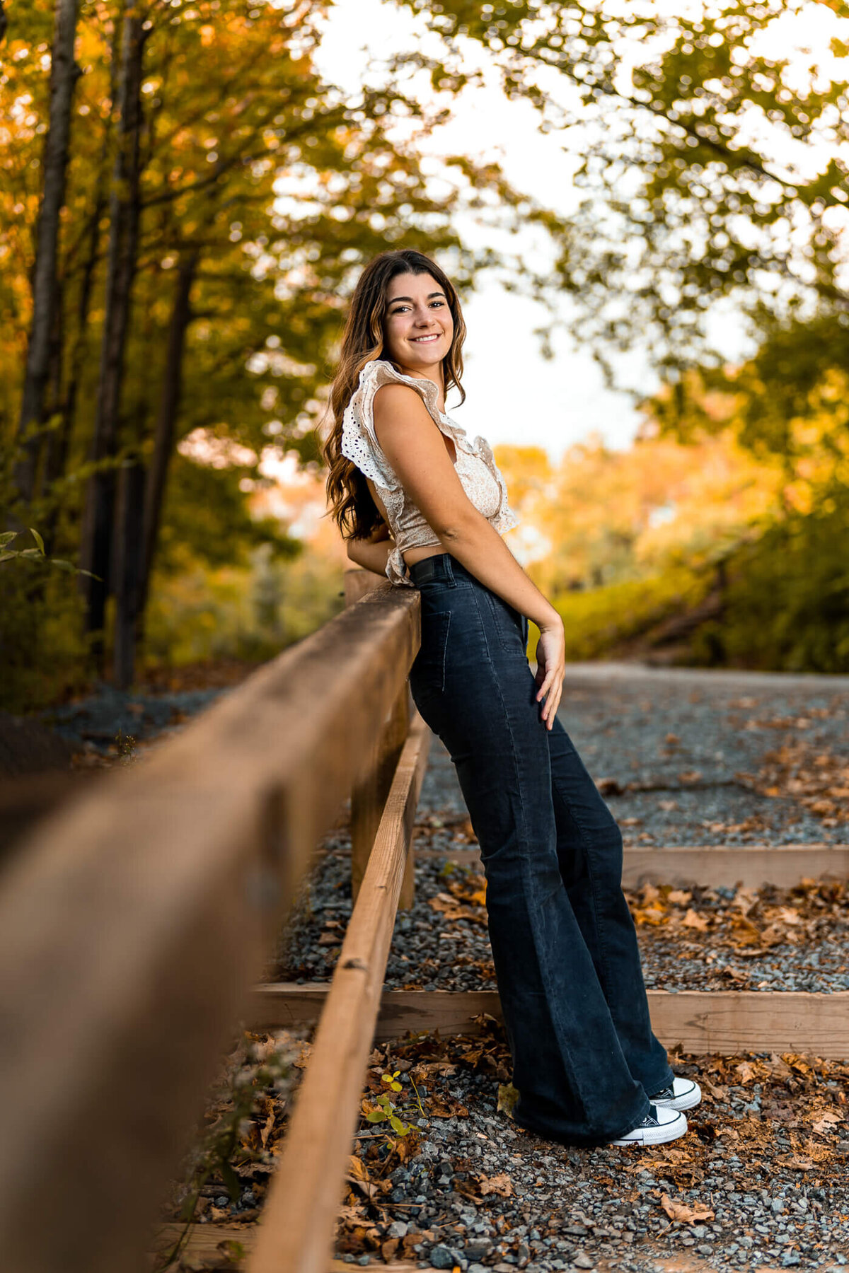 Pittsburgh senior photo of a senior smiling and leaning on a railing at a local park near Pittsburgh PA