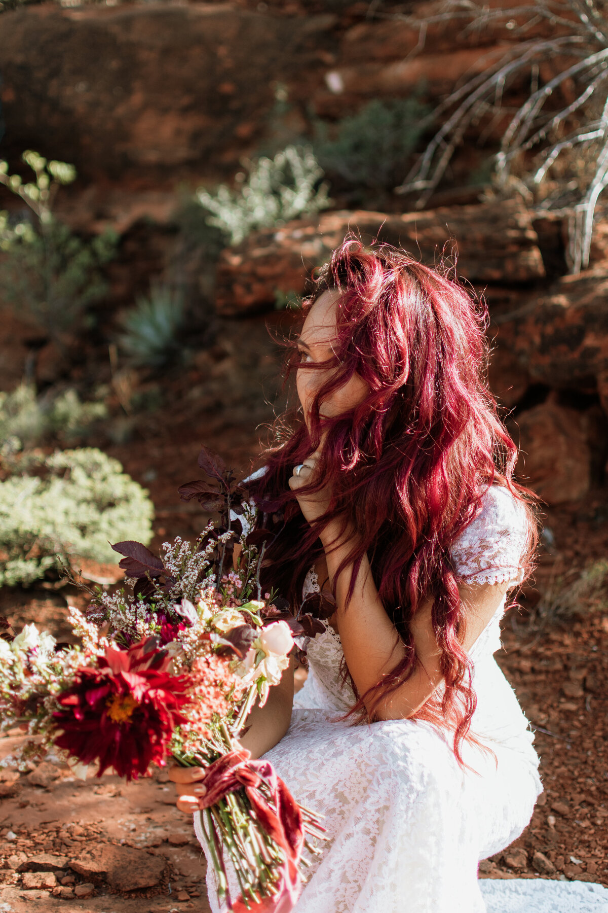 Bride with long red hair holding bouquet outdoors