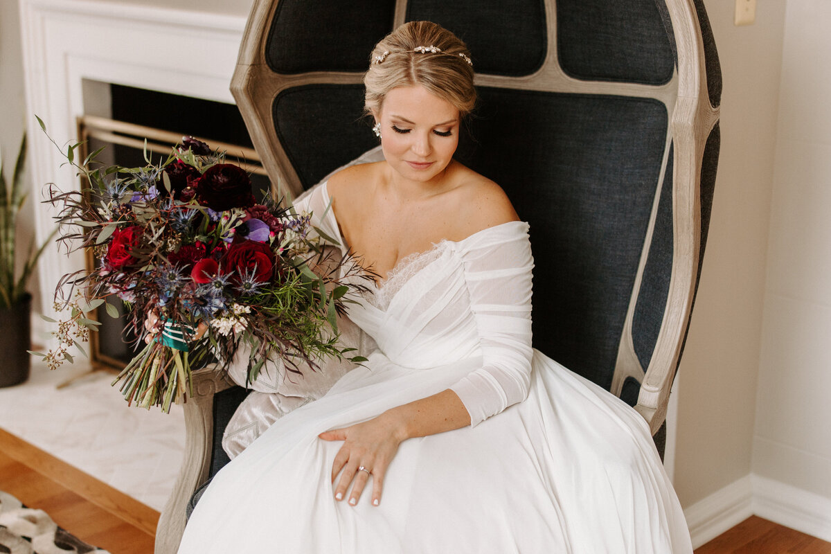 bride sitting down in a chair holding a large bouquet of flowers