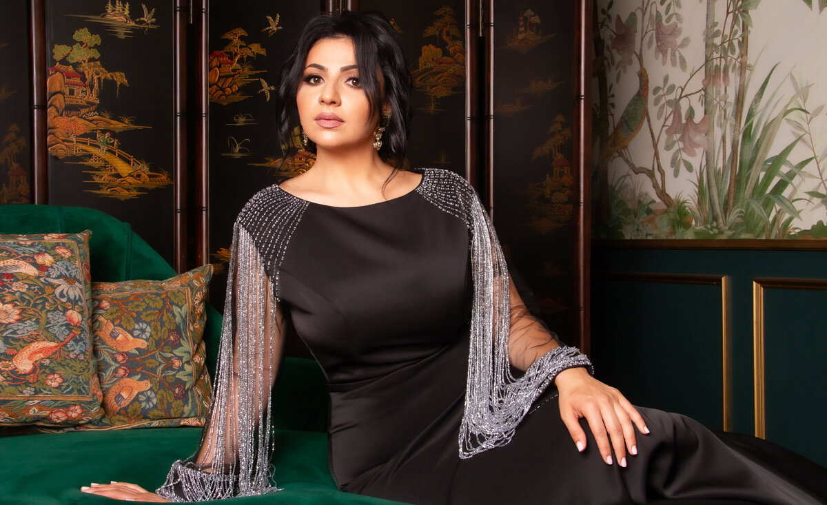 Classical musician portrait Azniv wearing black dress leaning against green chaise lounge