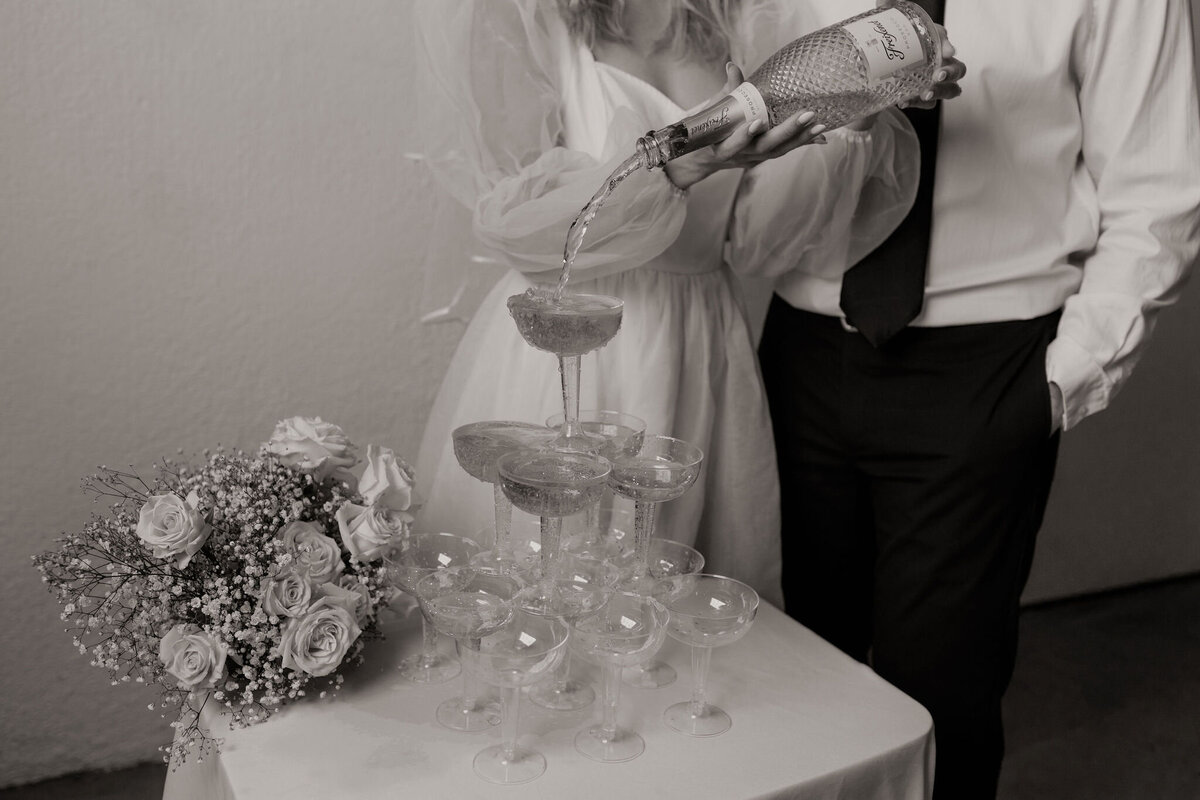 close up of bride pouring champagne into champagne tower