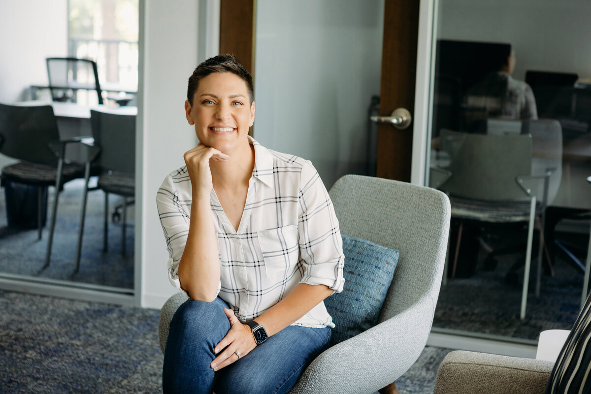 Woman smiles for brand photos in plaid blouse