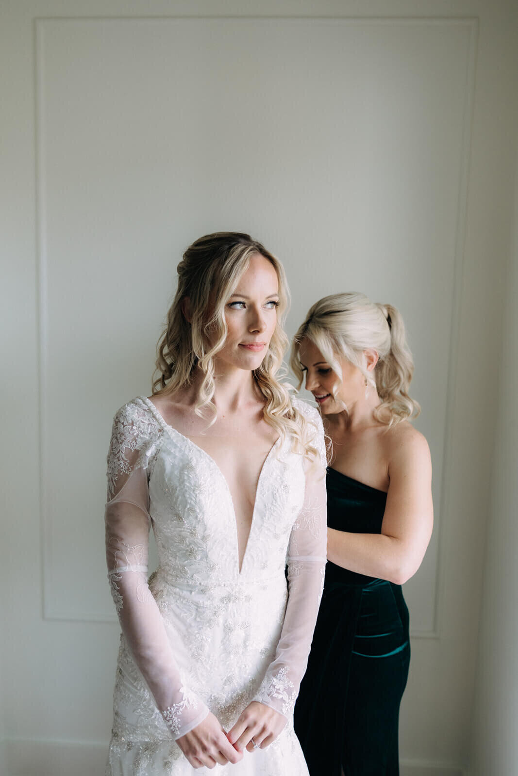 Bride being helped into dress by bridesmaid