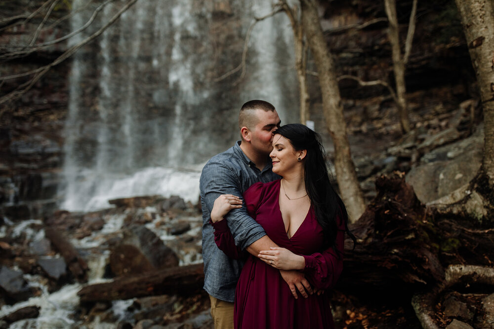 Bride and groom holding hands looking at each other while standing in front of rolling hills with the sunlight coming down on them