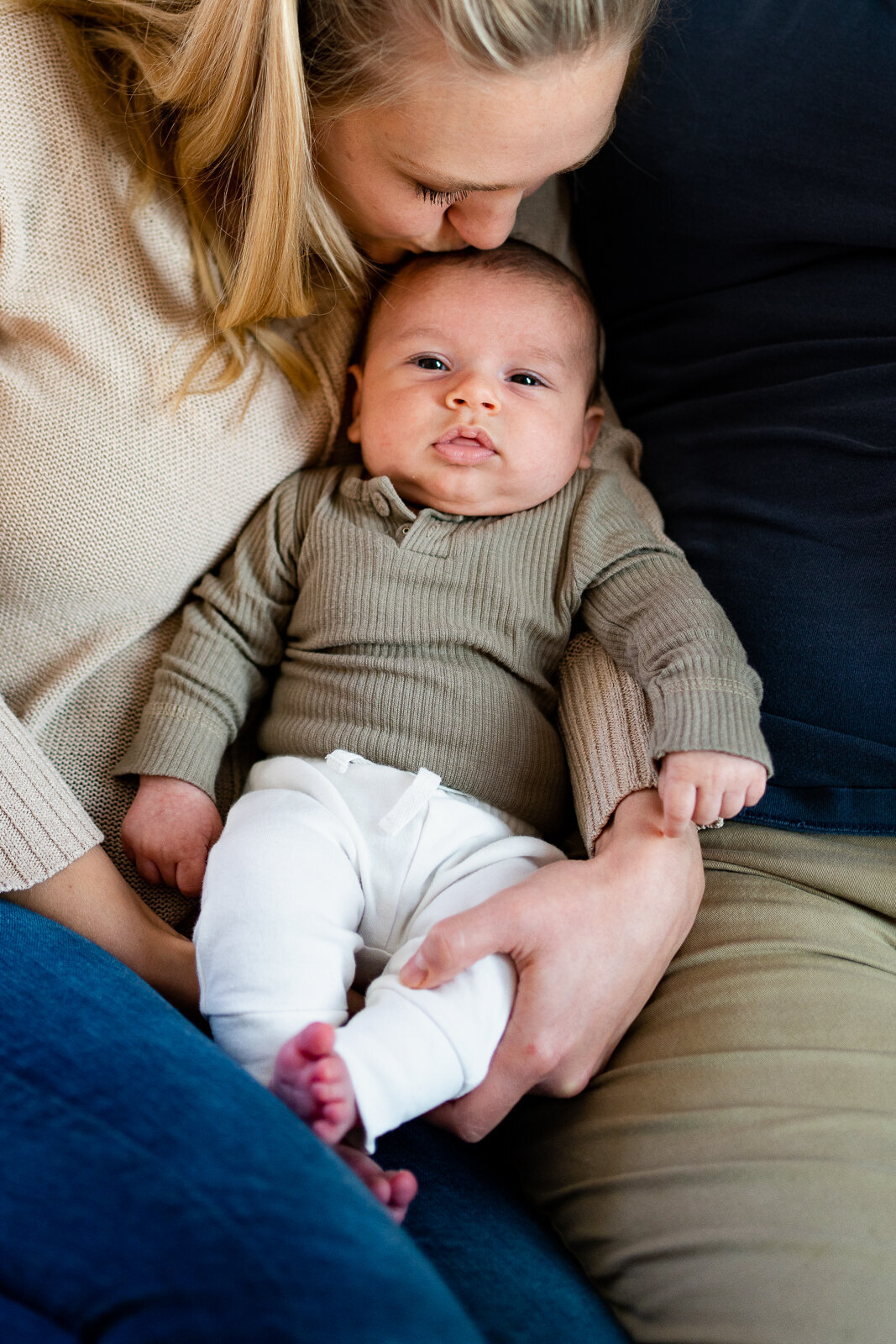 Baby boy being held by mom and getting kissed on his head during lifestyle photo shoot