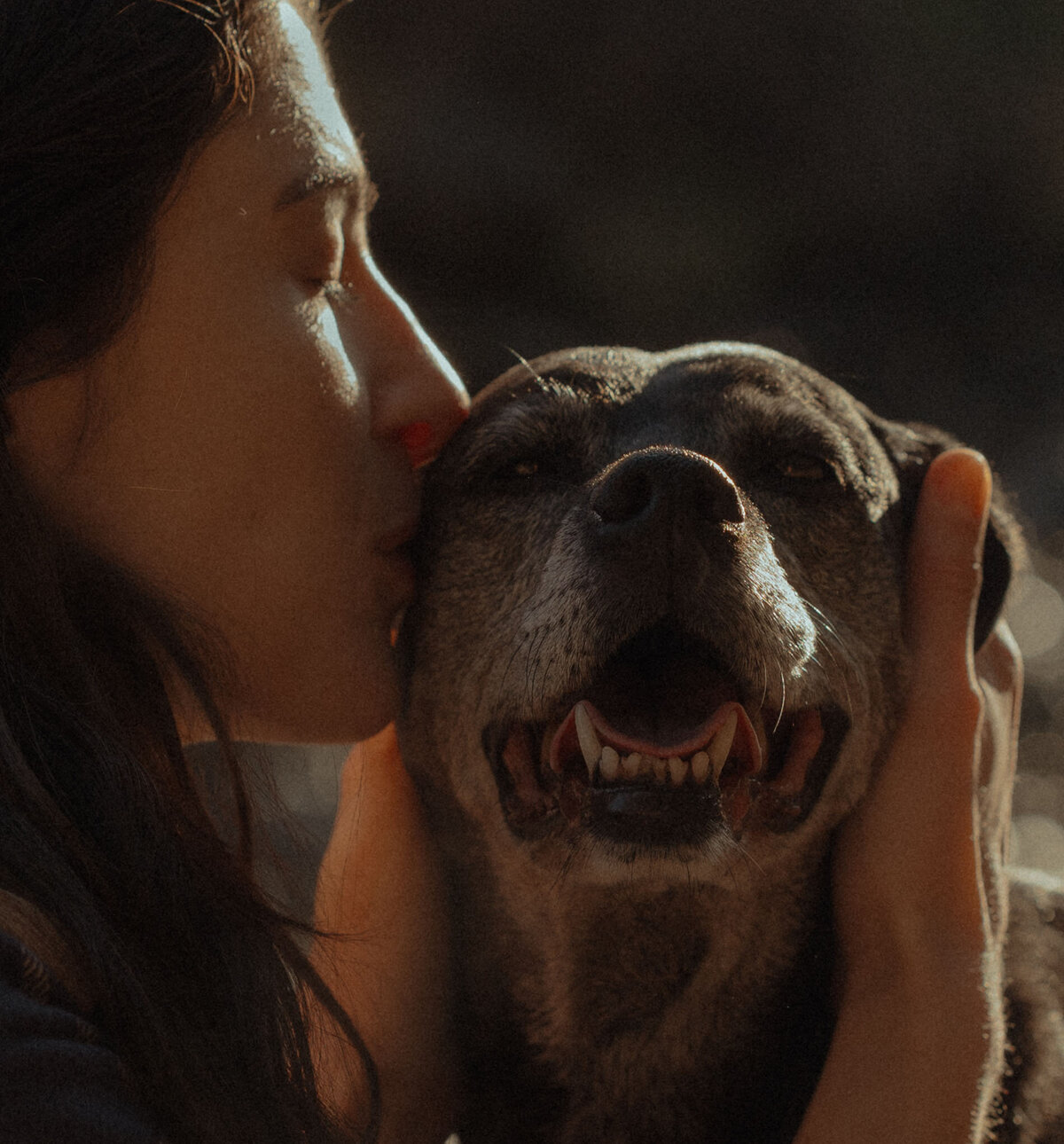 woman kisses her dog on the head while dog smiles at camera in Bend, Oregon