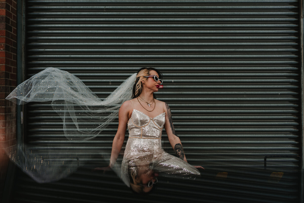 Creative urban photography of a bride with her veil blowing in the wind
