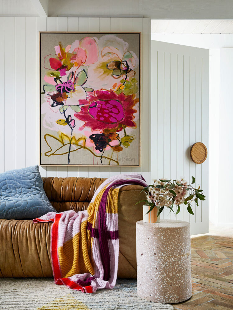 Cosy corner sofa styled with knitted throws and floral artwork by Melbourne residential interior design studio Lisa Hunter Interiors.