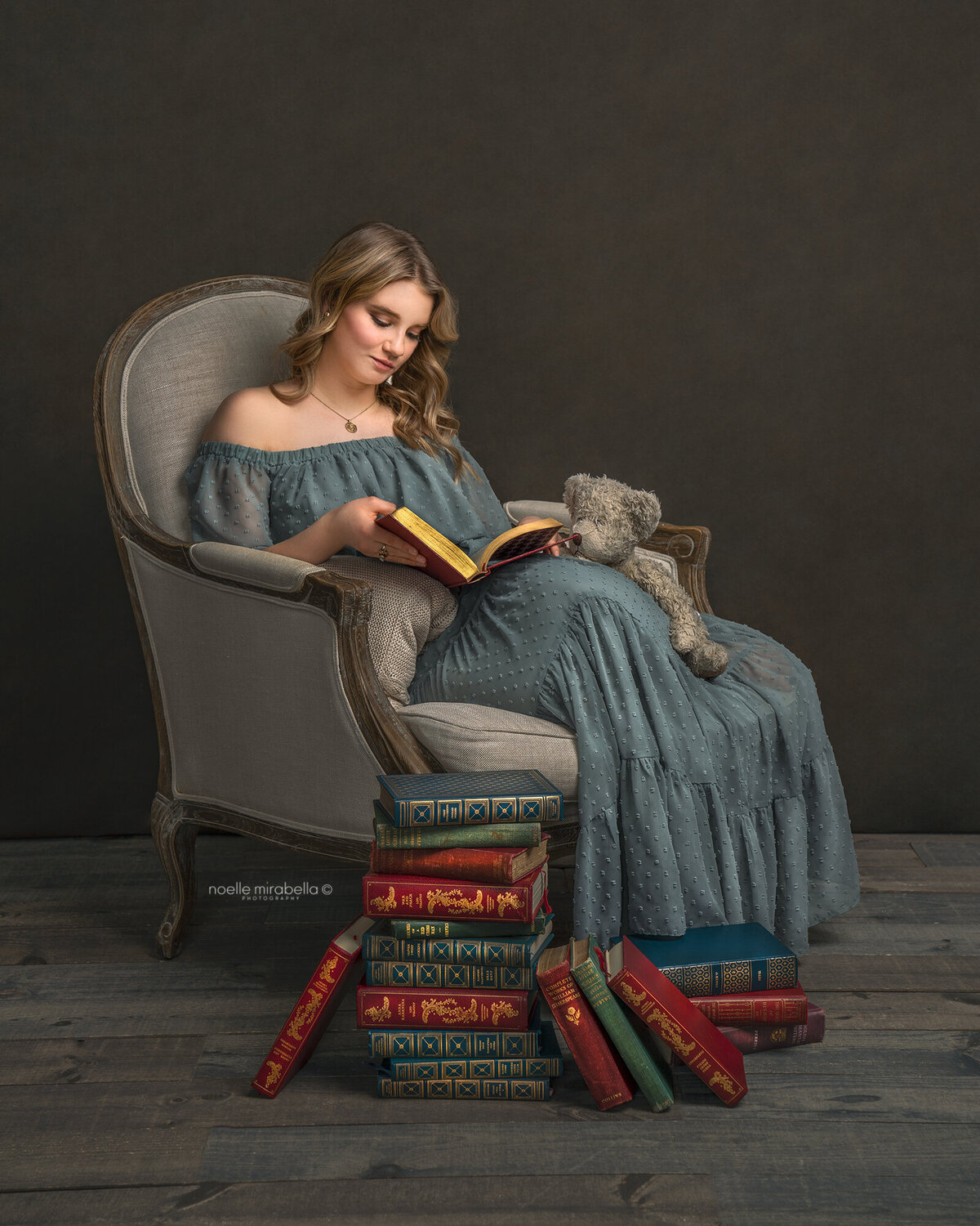 Young lady sitting in a vintage French chair reading antique books.