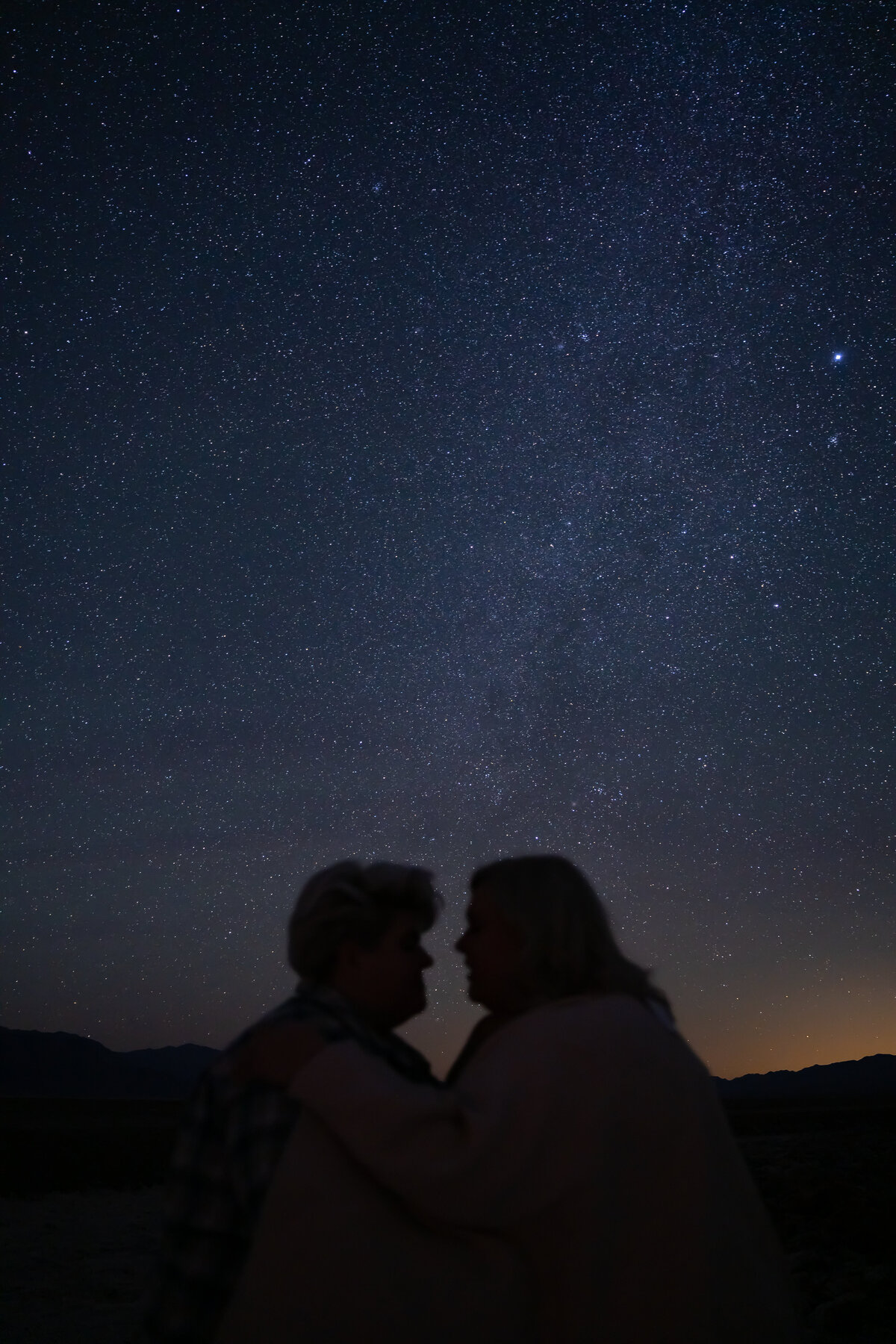 A starry night with the silhouette of a couple about to kiss