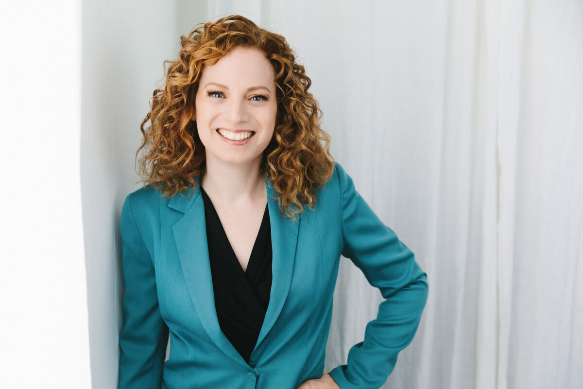 Red haired woman wearing blue blazer and smiling at viewer