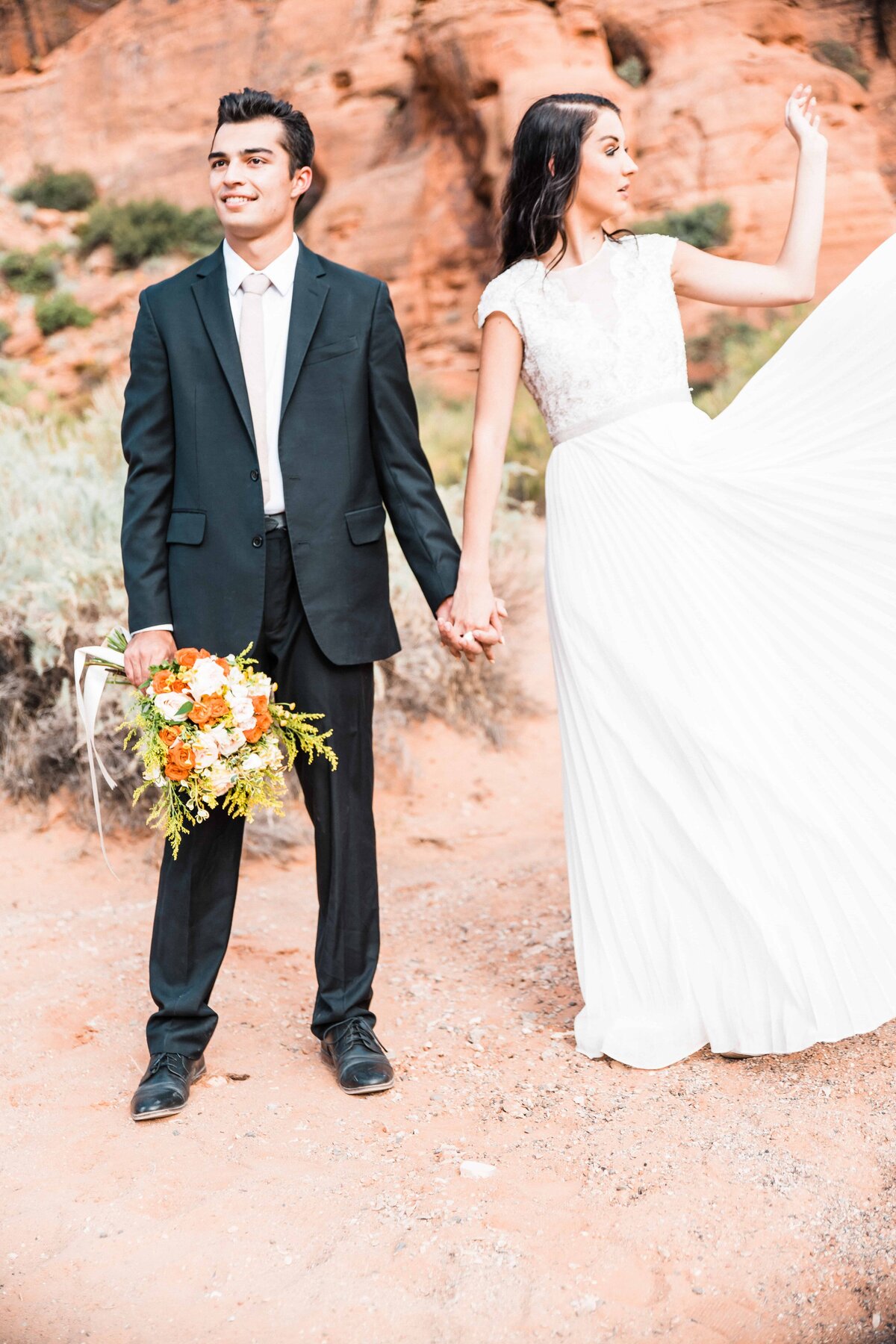 The bride's dress flies as the bride and groom pose for photos at this southern Utah elopement