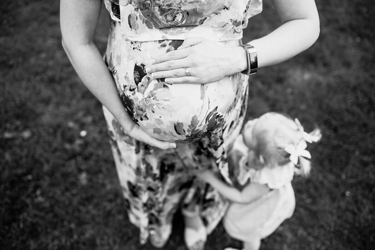black and white maternity photo of mom holding belly and daughter