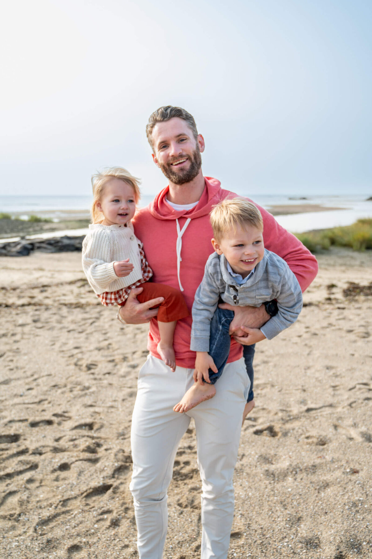 Dad holding 2 toddler at a beach family session in Connecticut.