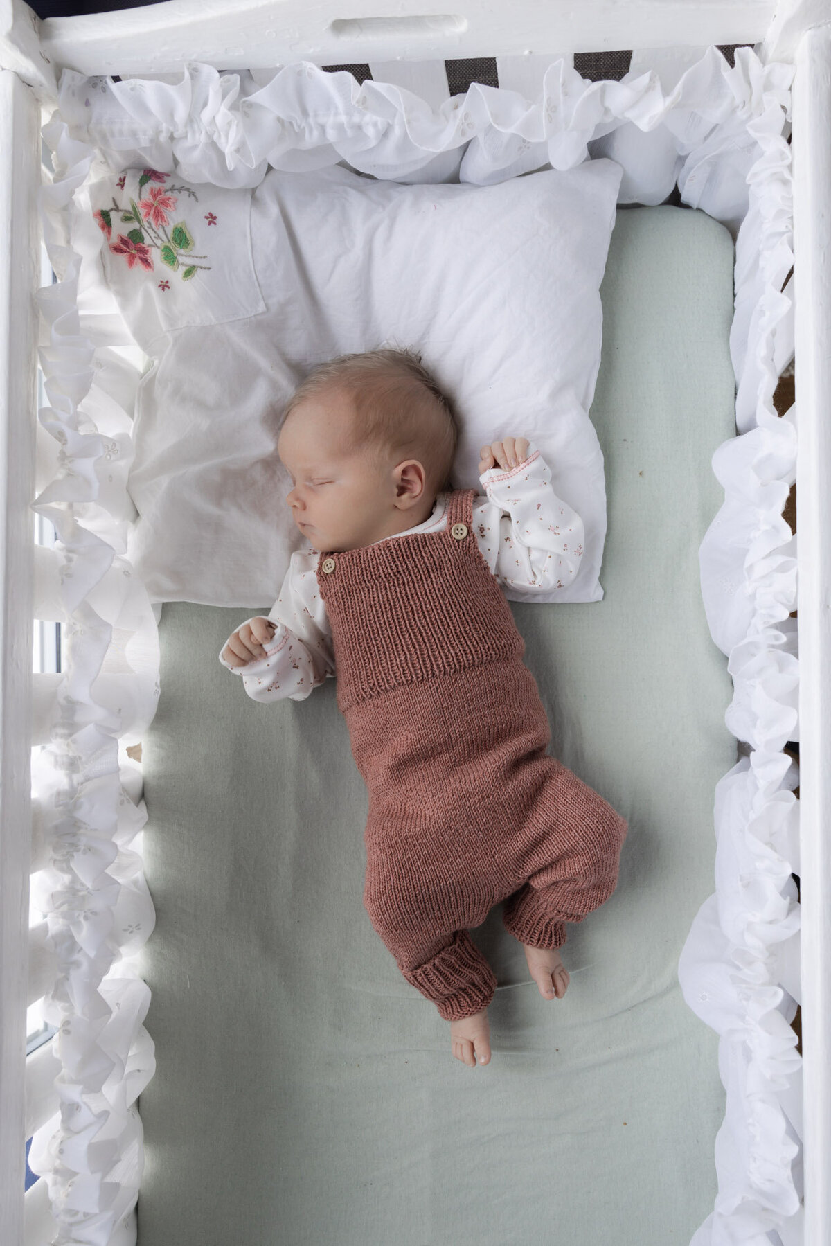 Livsstilsfoto oversiktsbilde av baby i babyseng, fotografert ovenfra og ned.