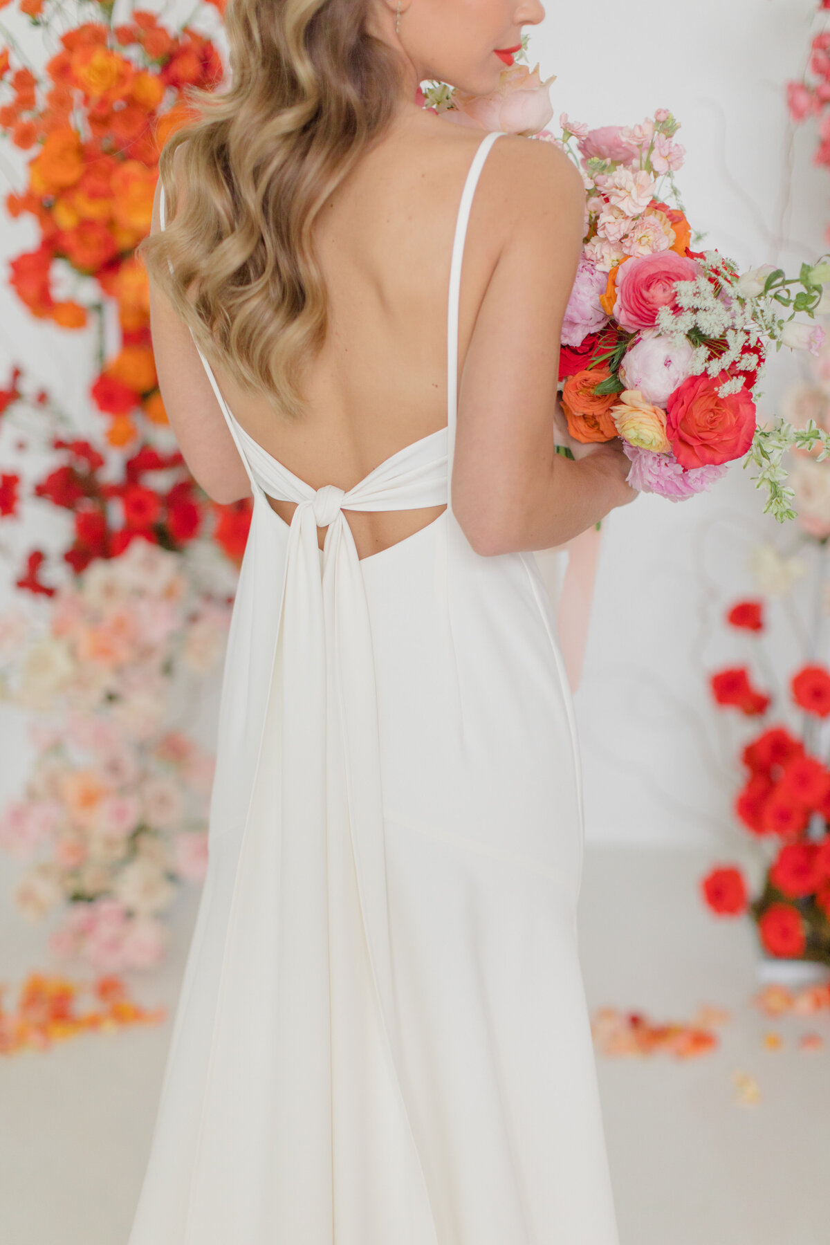 bride holding bright florals in red, peach and pink