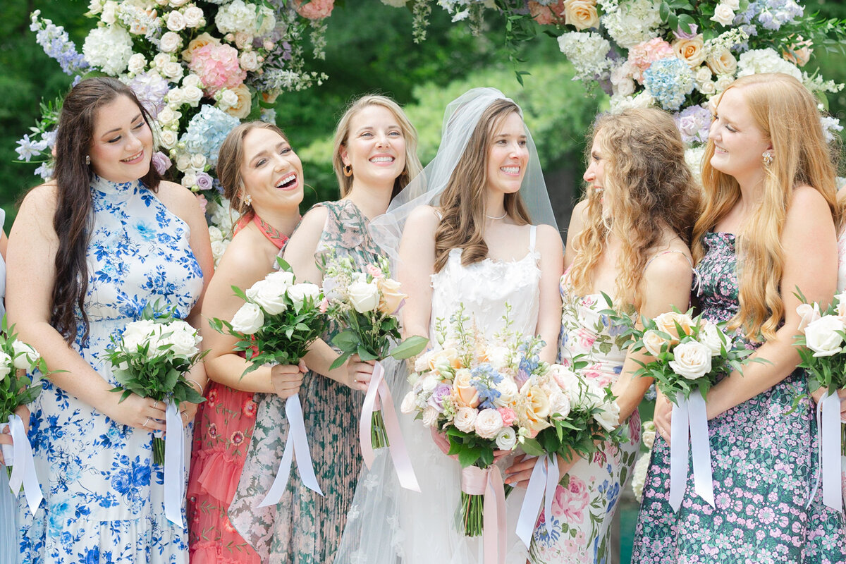 bridesmaids laugh together under a floral arch in Columbus Ohio