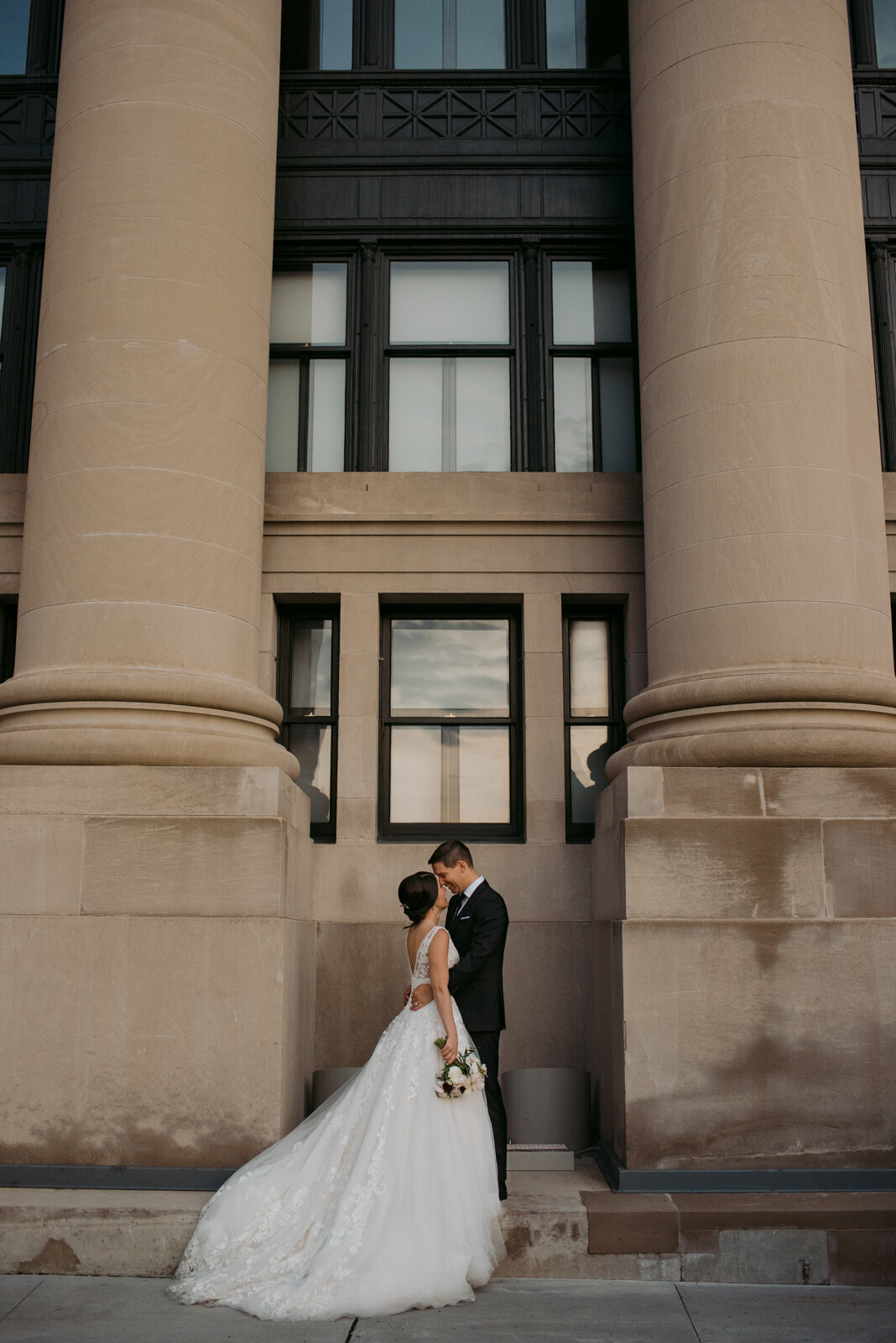 bride and groom kissing between castle pillars