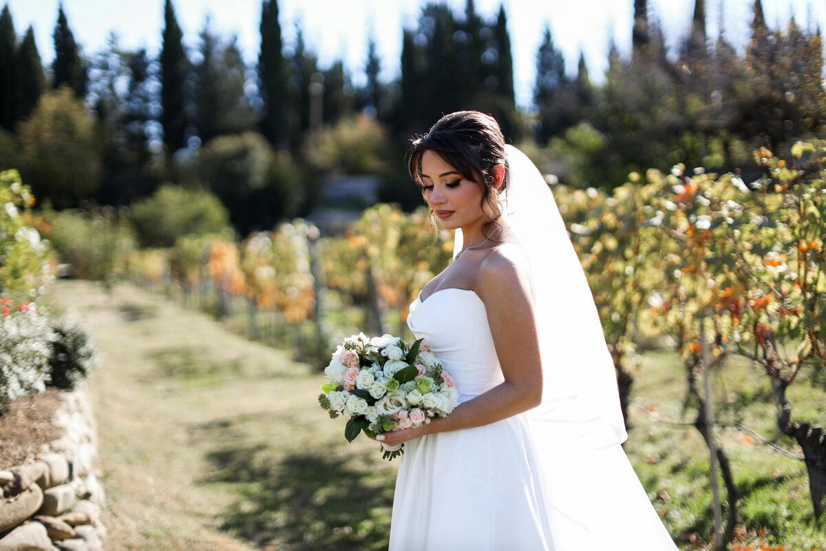 A bride signs the wedding register while her new husband holds her hand.