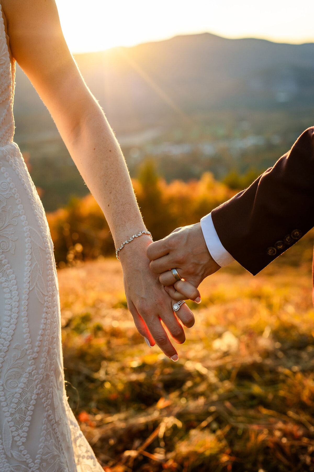 Bride and groom holding hands showing off wedding bands at sunset by NH Wedding Photographer Lisa Smith Photography