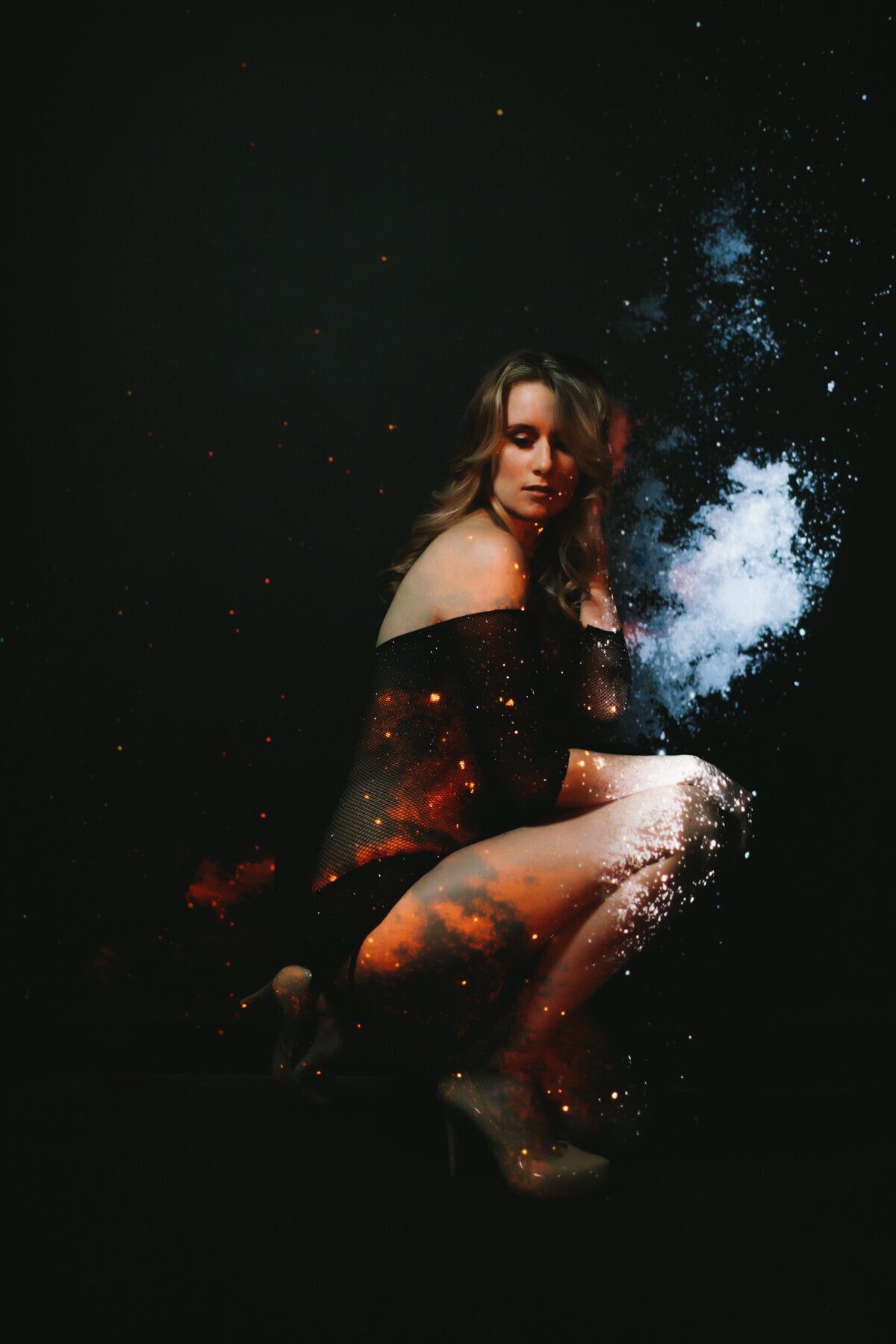 Woman posed kneeling with galaxy projected onto her skin