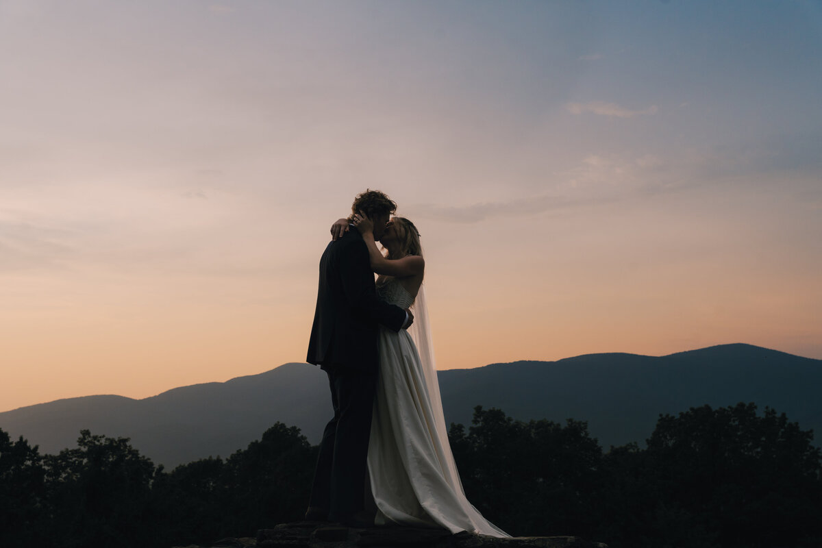 couple sealing their mountain elopement with a kiss during sunset 