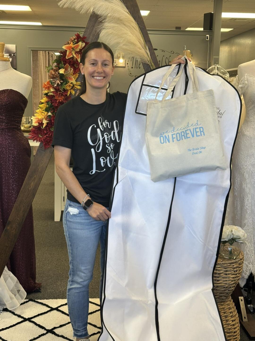 Woman holding a garment bag and tote bag inside a bridal shop