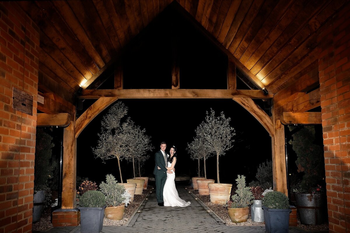 Bride and groom embracing and laughing out loud under a beautifully lit archway 