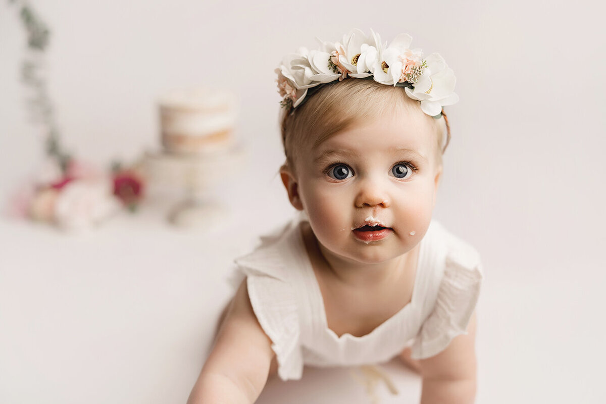 Adorable baby girl with big blue eyes and cake for her birthday