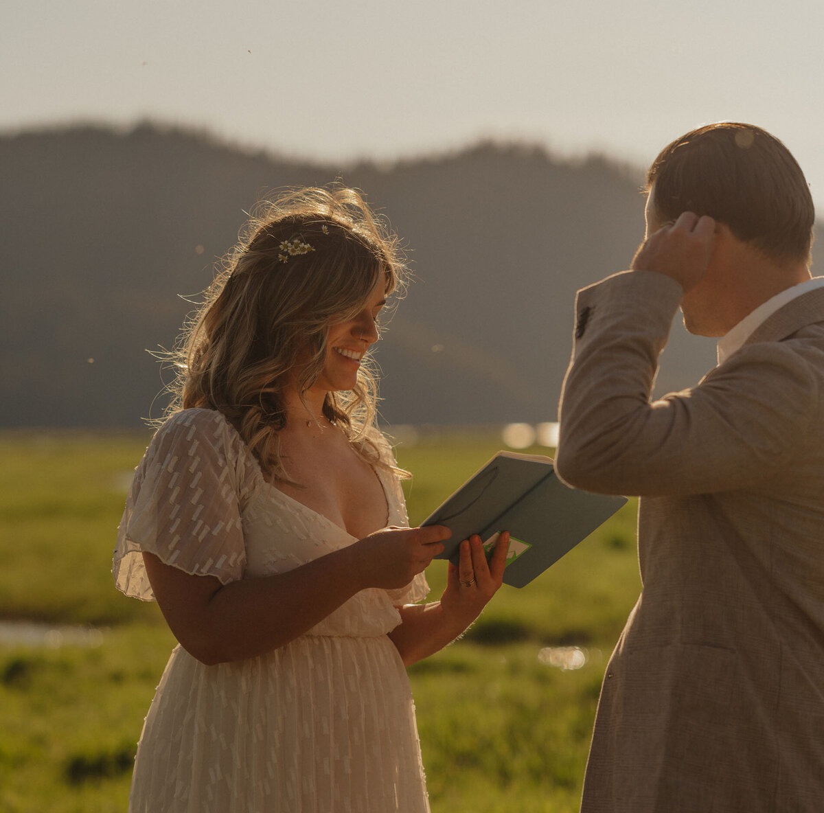 bride smiles and reads vows to groom in the alpenglow light at Sparks Lake in Bend, OR