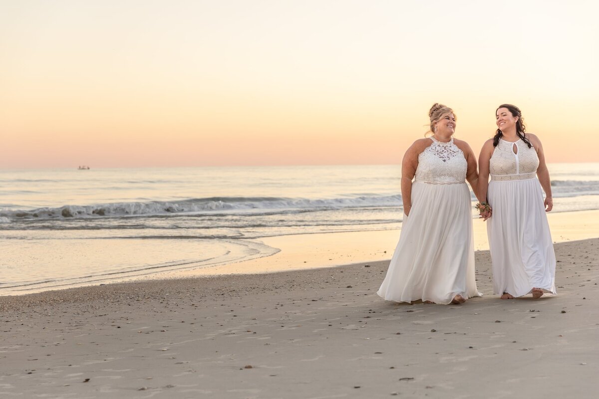 Two brides walk on beach