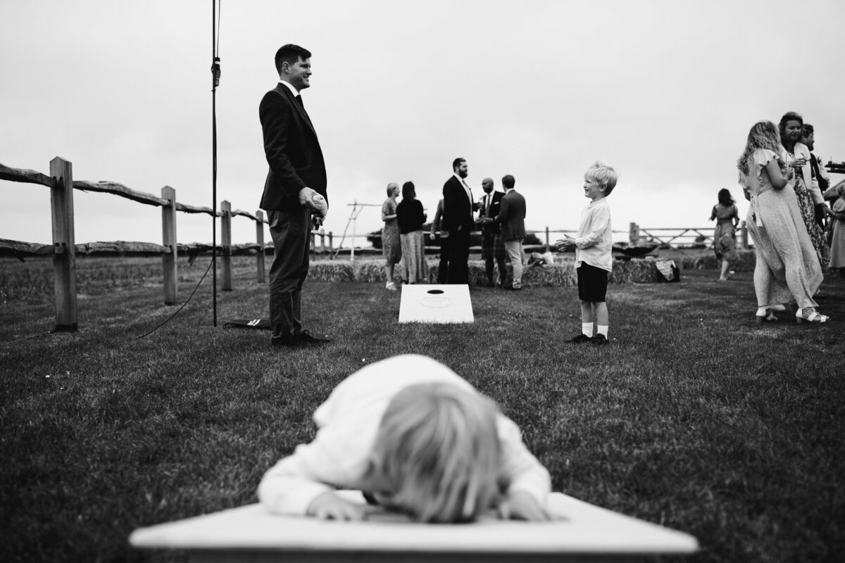Black and white photo of kids playing field games at outdoor wedding reception