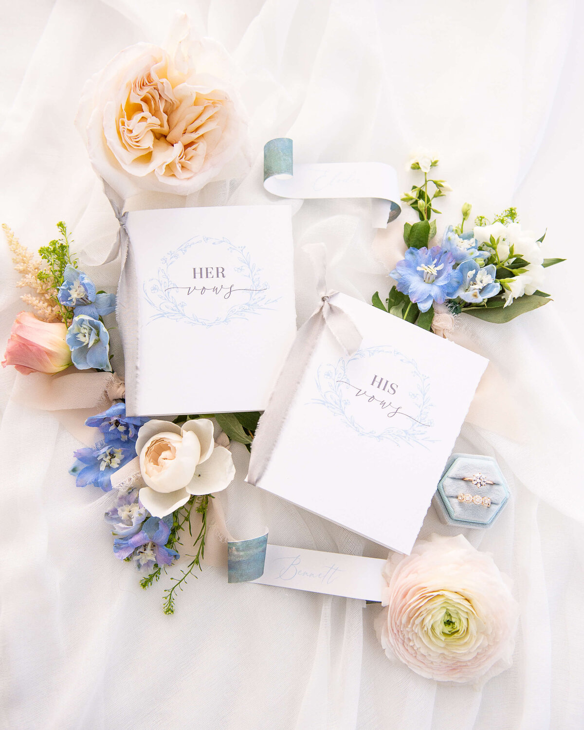 Ottawa wedding photography showing a flat lay of blue, blush and white flowers, Stor by Margot engagement ring  and wedding vows