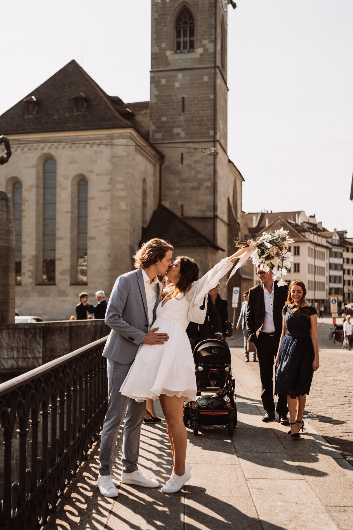 Ein frisch verheiratetes Paar feiert ihren Moment auf einer Brücke in Zürich nach ihrer Ziviltrauung. Die Braut hält freudig ihren Blumenstrauss in die Luft. Authentische und ungestellte Hochzeitsfotografie von Stories by Jane, die die Freude und Liebe eures besonderen Tages einfängt.