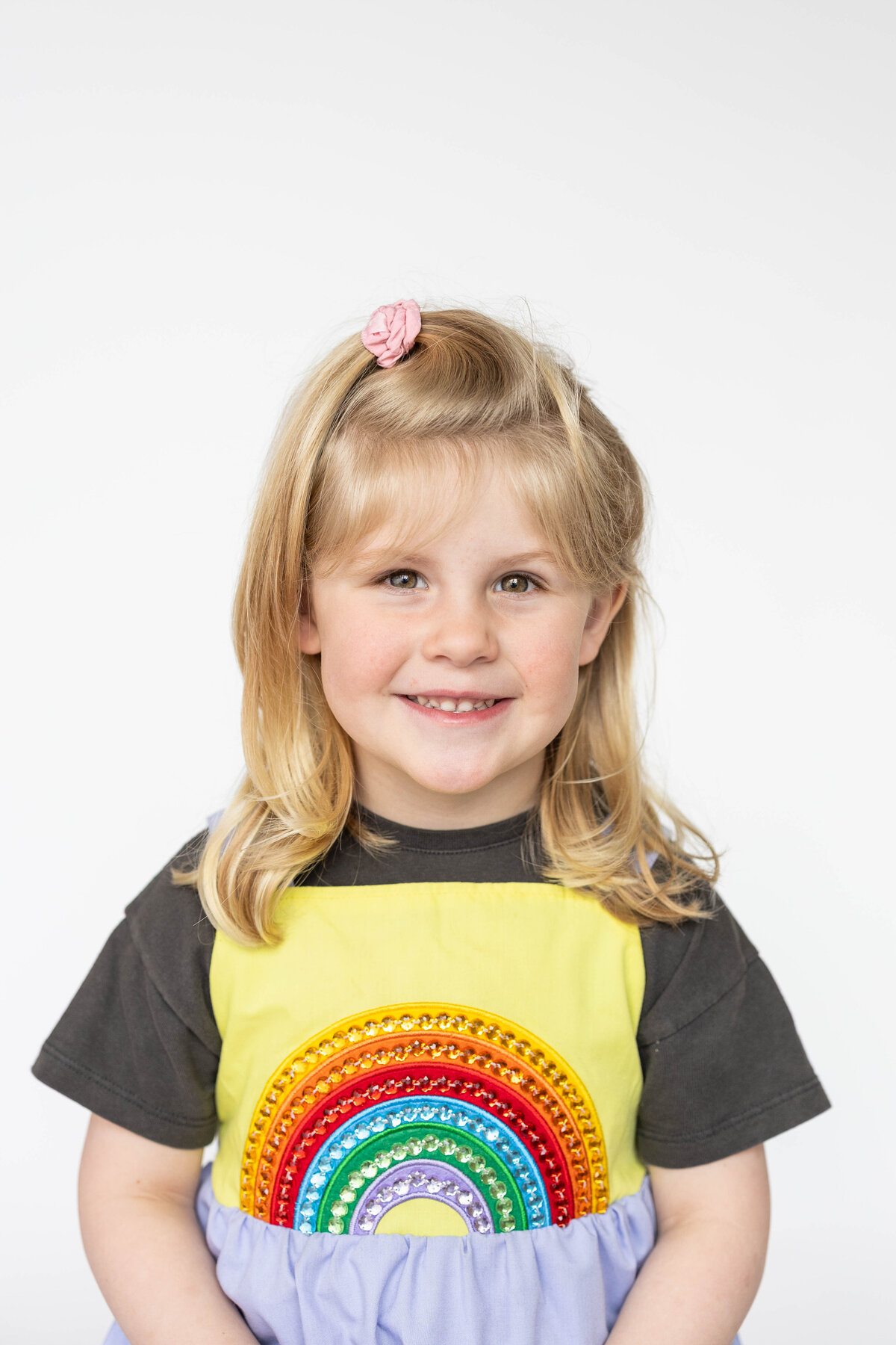 Little girl with rainbow dress sits for her school photo