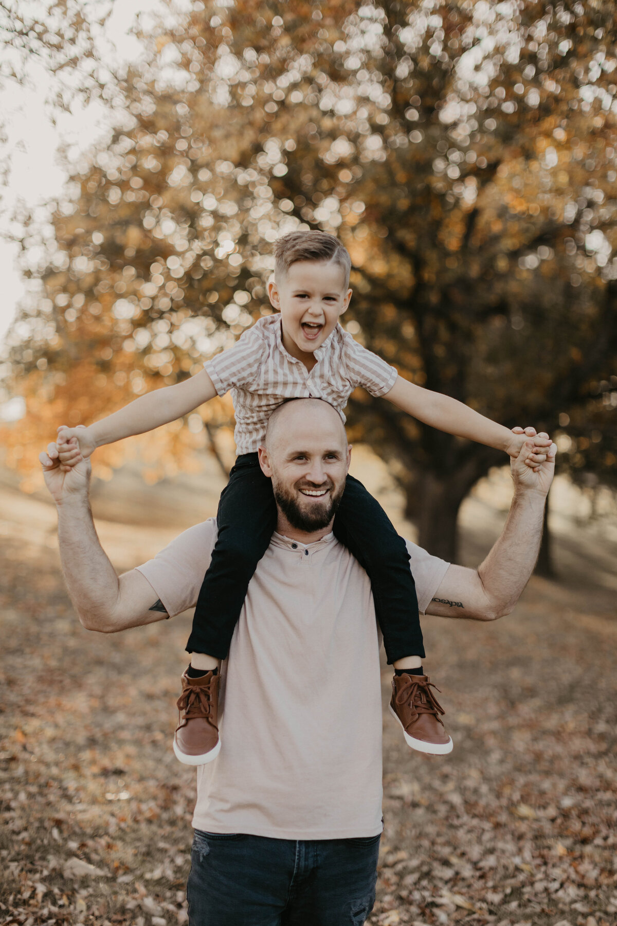 Young brother sitting on dad's shoulders. 