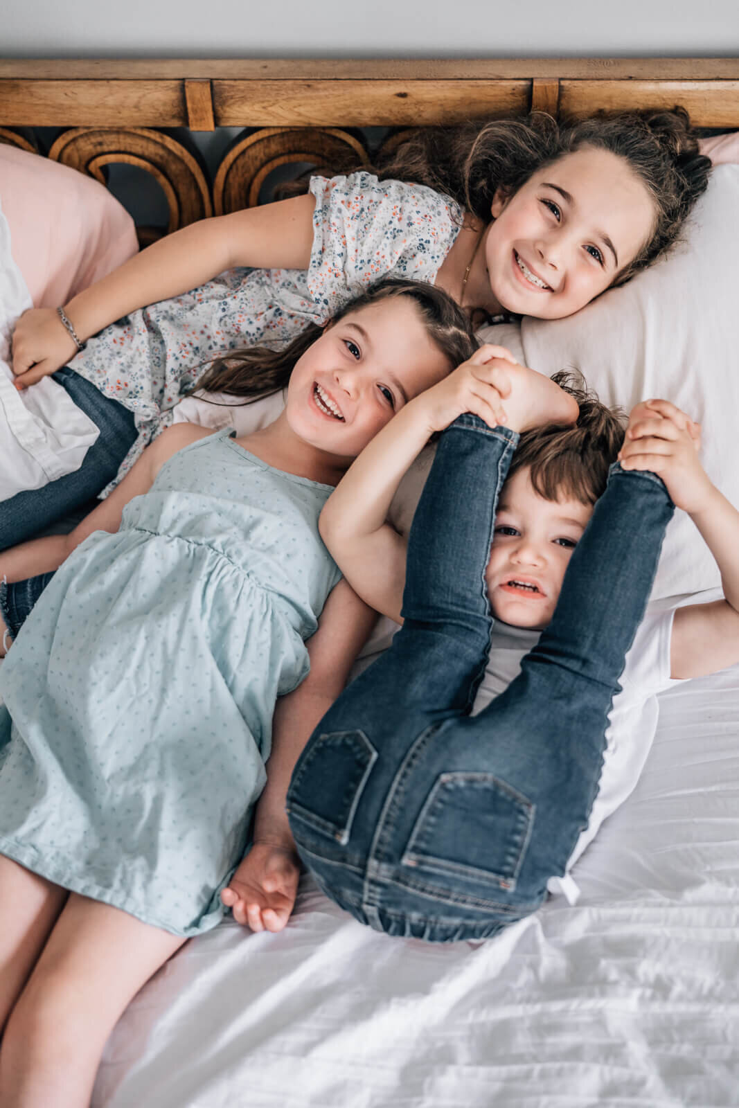 Three silly siblings playfully pose for the camera during a shoot with maternity photographer Kate Simpson in Minneapolis.