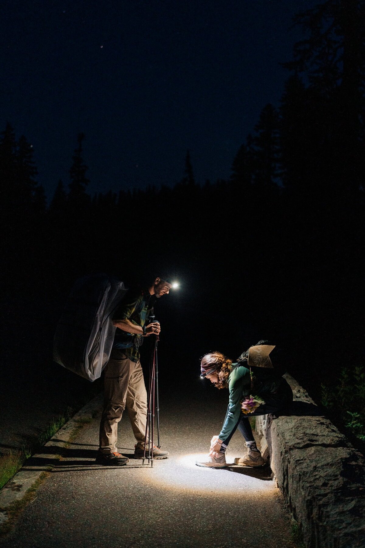 couple tying hiking boots with headlamps in the dark before their sunrise elopement in Mt Rainier National Park.