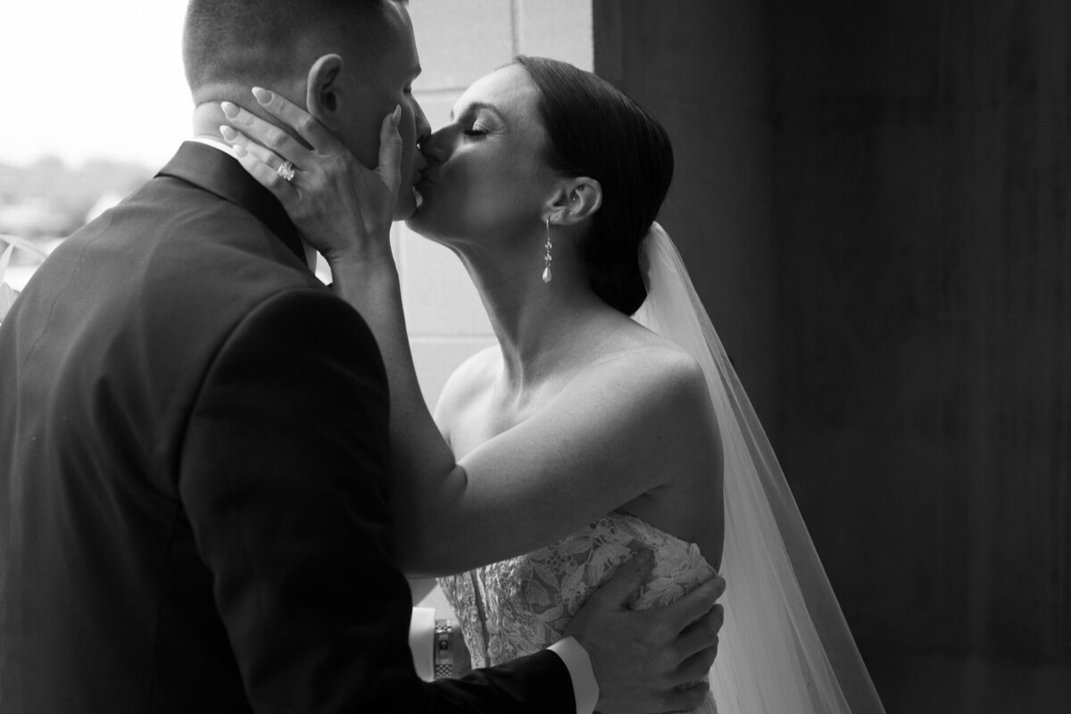 Bride kissing groom in emotional black and white wedding portrait