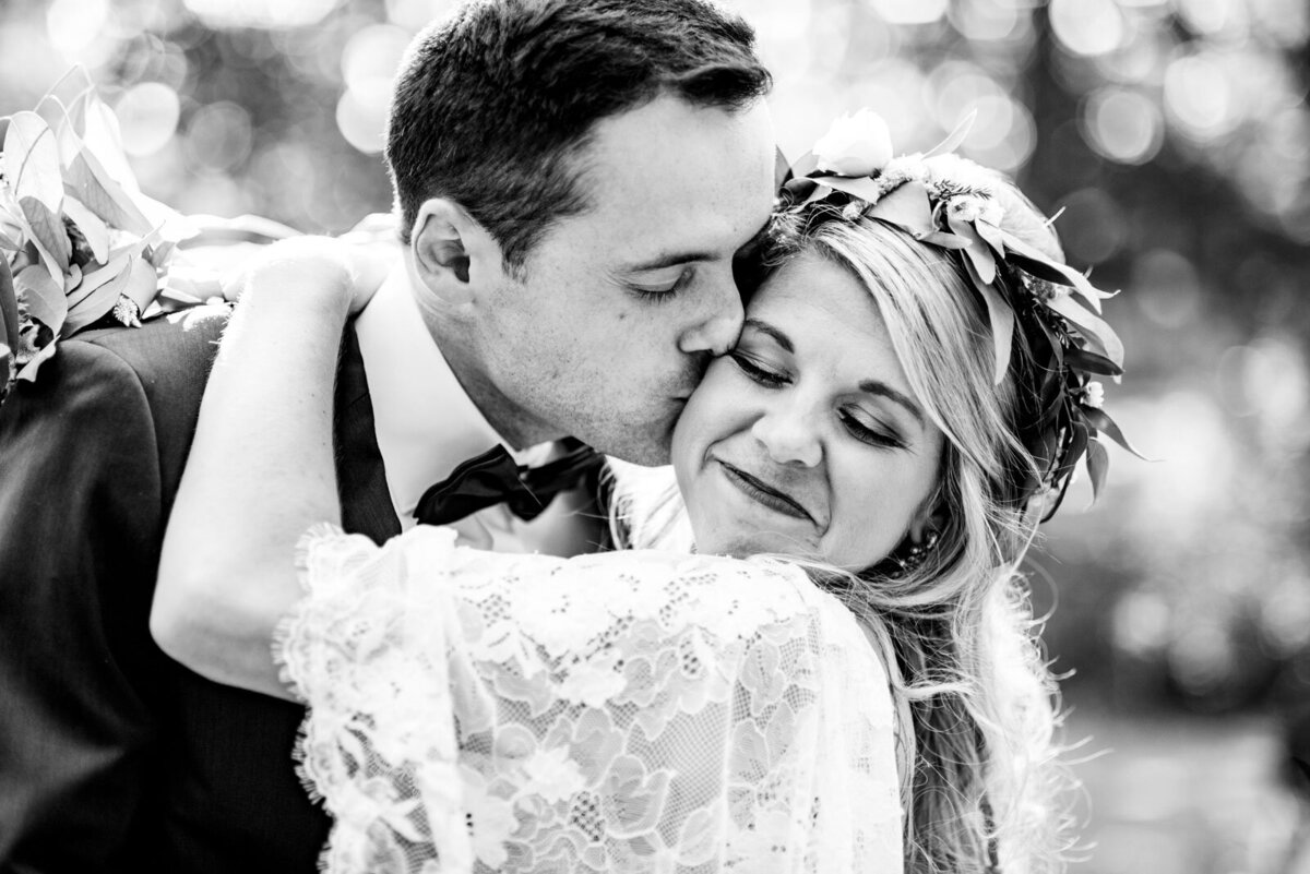 black and white photo of grrom kissing bride