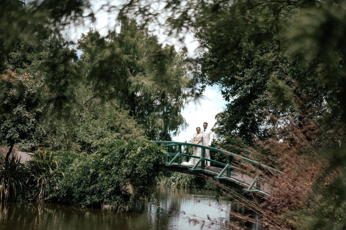 Bride and groom Tilly and Supun walking hand in hand over the bride at woodlands estate in waikato, photographed by Zanthe Vorsatz.