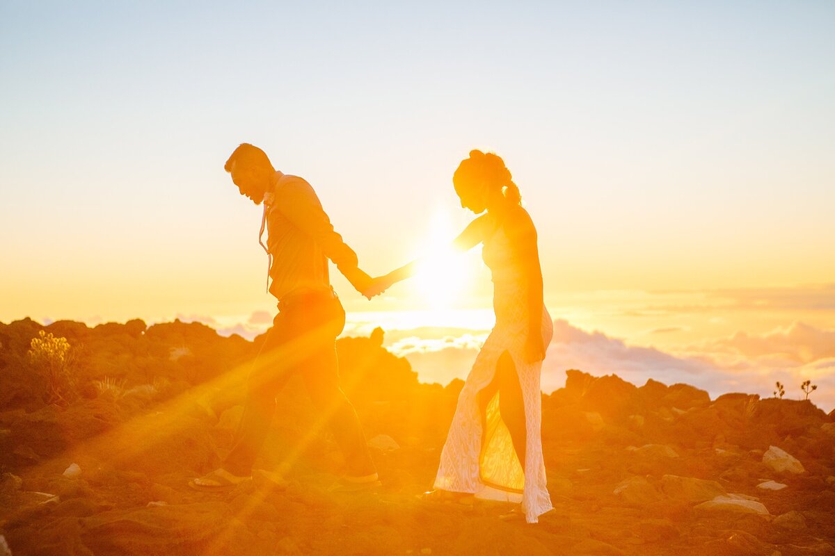 A bride and groom hold hands during sunset in Haleakala National Park