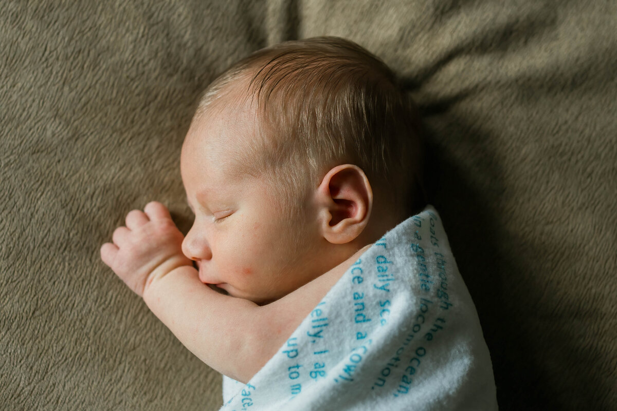 Baby laying in swaddle on bed
